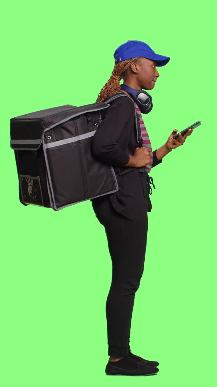 Vertical video: Woman delivering food in backpack and browsing internet
