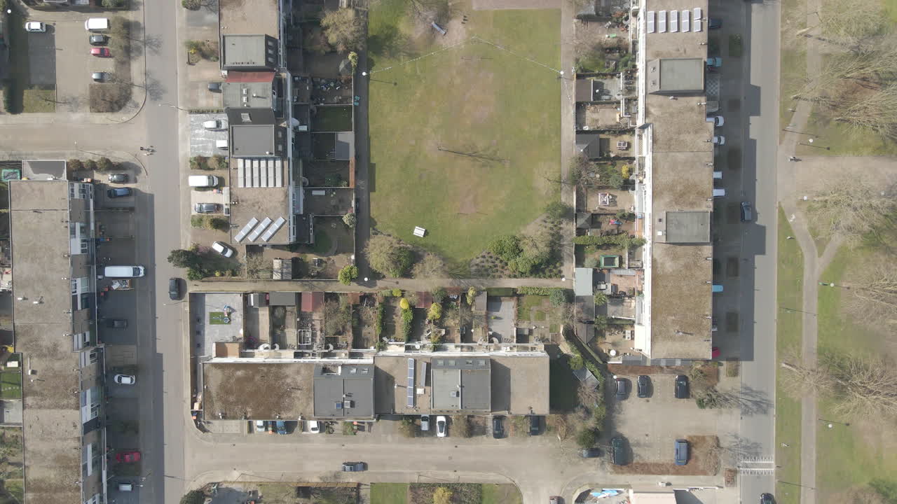 antena de arriba hacia abajo de casas en la azotea que rodean el parque verde - drone levantando