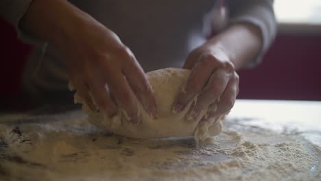 Woman's-hands-making-pizza-dough-on-a-marble-table-full-of-flour