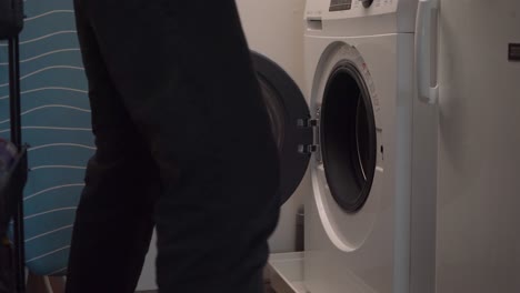 young man picks up laundry basket from front load washing machine