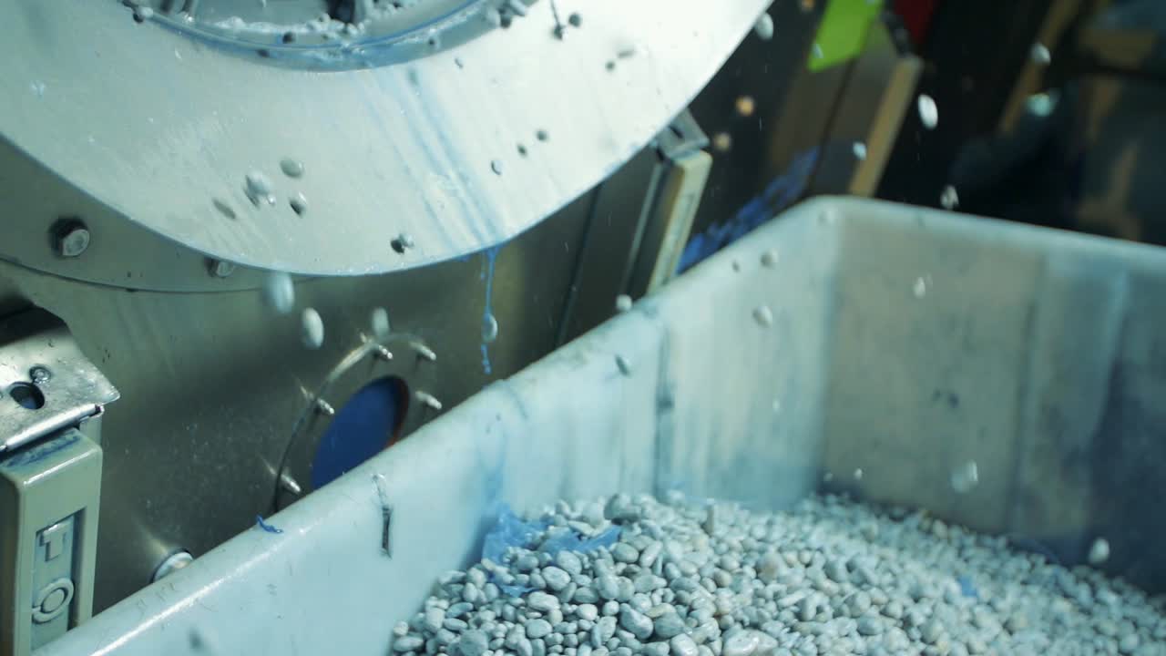toma en cámara lenta de piedras pómez saliendo de una lavadora industrial en una fábrica de jeans