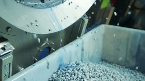 toma en cámara lenta de piedras pómez saliendo de una lavadora industrial en una fábrica de jeans