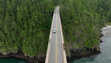 overhead aerial shot of a car driving over deception pass bridge in washington state