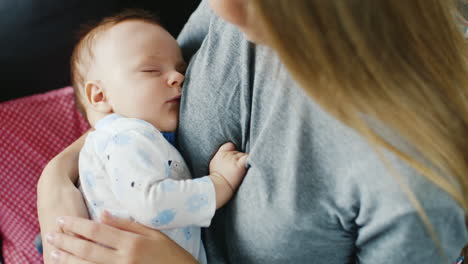 baby sweetly sleeps in the arms of her mother rear view over the shoulder