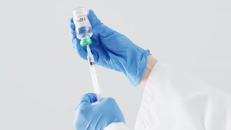 video of hands of doctor in surgical gloves filling syringe with hpv vaccine, with grey copy space