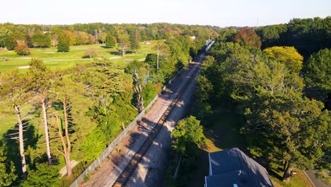 Aerial-view-of-passenger-train-running-on-interstate-track-laid-amidst-countryside-greenery