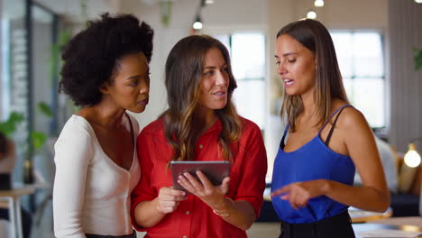 female multi-cultural business team with digital tablet in modern open plan office