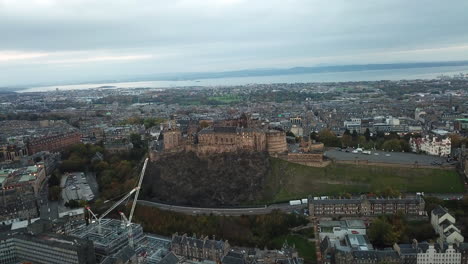 Spektakuläre-Drohnenaufnahme-Von-Edinburgh-Castle-Bei-Sonnenaufgang,-Die-Aus-Der-Ferne-Beginnt-Und-Sich-Langsam-Nähert,-Um-Das-Beeindruckende-Gelände-Zu-Enthüllen