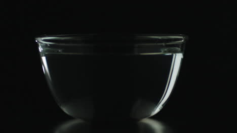 slow motion of chili dropping in bowl of water