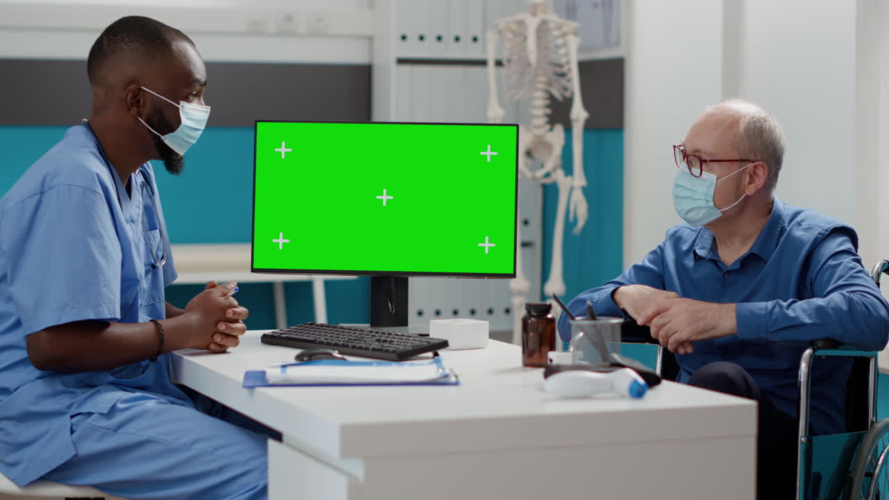 Doctor consulting with patient in front of green screen monitor