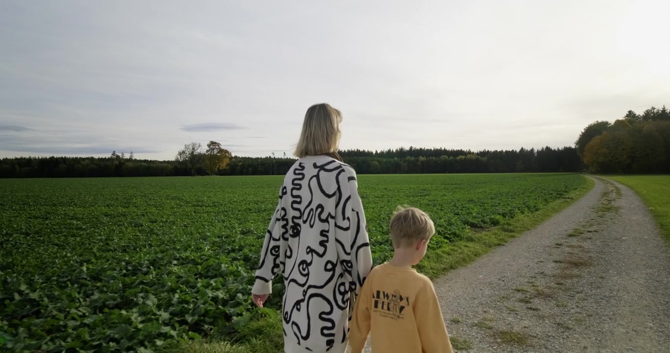 Nella bellezza autunnale, una madre e un bambino passeggiano attraverso una campagna vibrante, catturando l'essenza della famiglia e la gioia stagionale in un viaggio tranquillo.