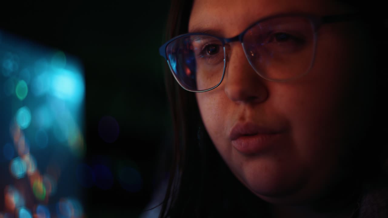 mujer adulta joven con gafas reflectantes analizando datos de código de seguridad cibernética trabajando de noche concentrando pantallas de ordenador | criptomoneda virus financiero hacker mujeres cuarto oscuro programador 4k