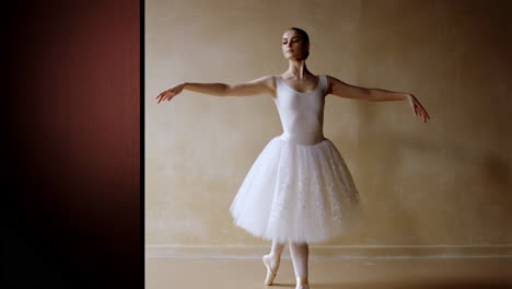 young ballerina in white tutu posing in a ballet studio