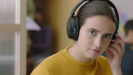 close up portrait beautiful young caucasian woman student listening to music wearing headphones working in busy modern office