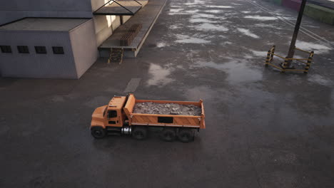 a dump truck loaded with gravel is parked outside a warehouse