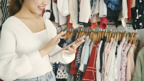 entrepreneurs and small business owners of fashion store using digital tablet to check stock on rails in clothing store.