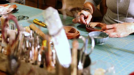 Mid-section-of-craftswoman-preparing-leather-belt