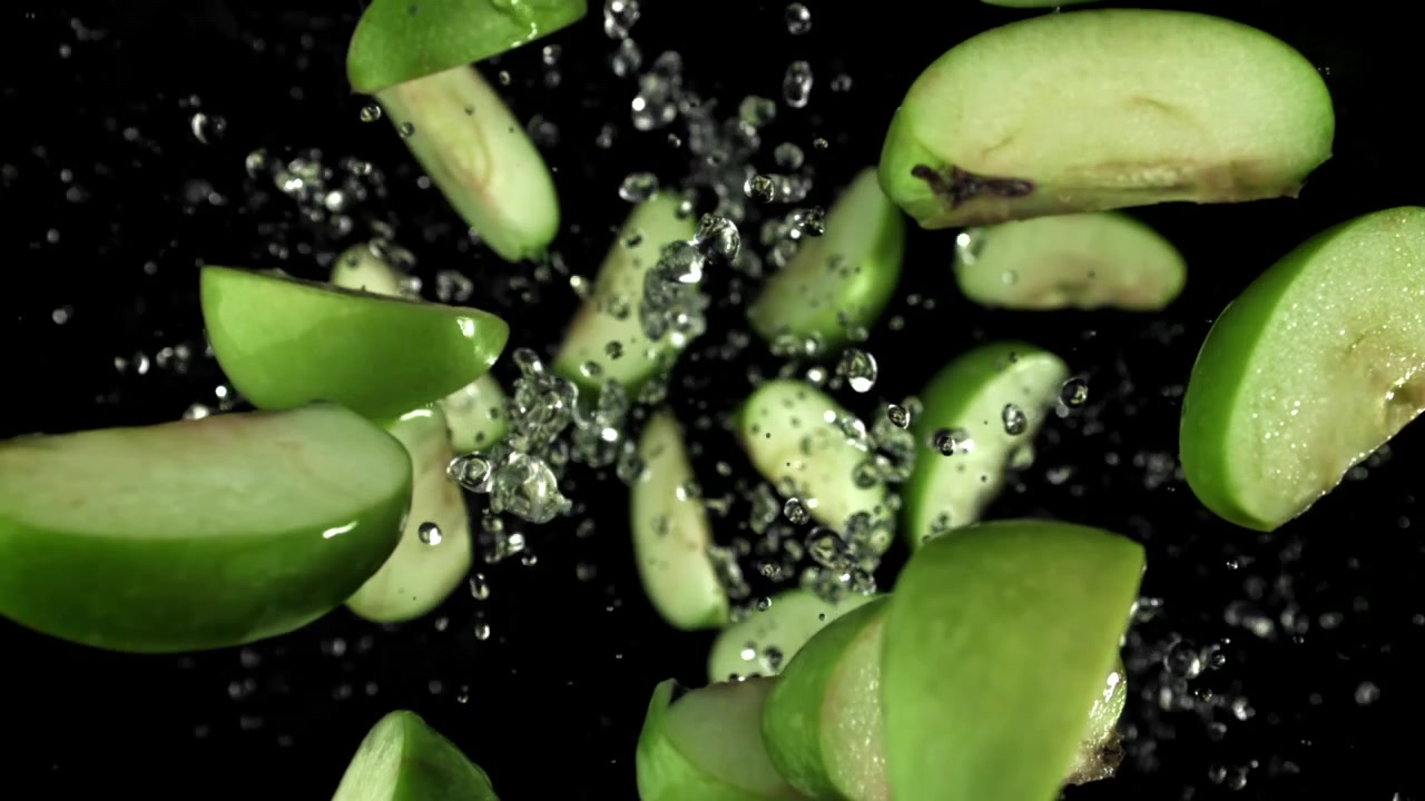 Fette di mela verde che cadono con schizzi d'acqua in super slow motion