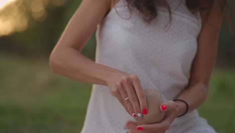 A young woman sculpts an object from clay in an open area in nature laughs enjoys the process. Women&#039;s hands are molded from clay in close-up