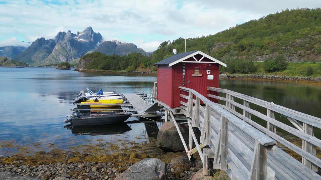 muelle, botes y cabaña roja en tennstrand, islas lofoten, noruega - pan izquierda