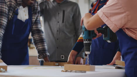 Close-Up-Of-Trainees-In-Workshop-Learning-How-To-Use-Power-Tools-To-Assemble-Bicycle