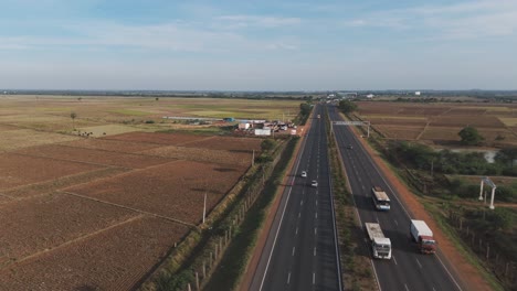 aerial drone shot of highway with traffic passing with open field
