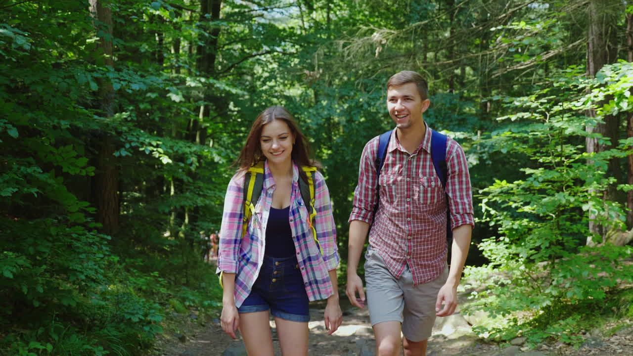 젊은 매력적인 부부는 숲 하이킹과 활동적인 라이프스타일을 걷고 있다