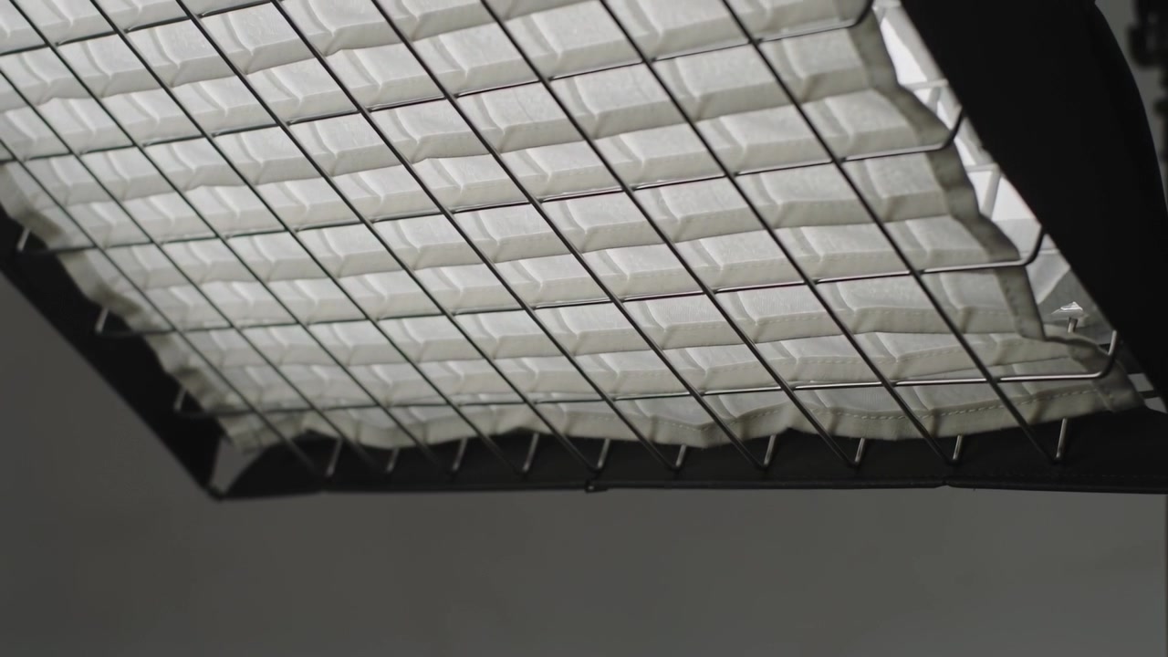 Droplet forming on metal grid edge, softbox eggcrate grid elongating detaching at studio ceiling