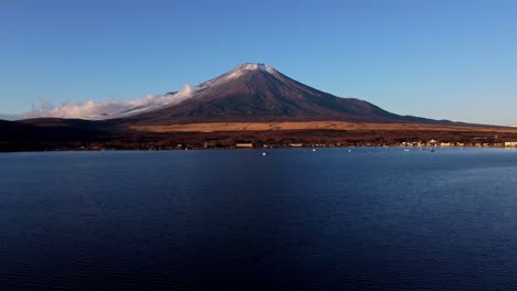 Majestic-Mount-Fuji-towers-over-Lake-Kawaguchi-at-dusk,-clear-skies-enhancing-the-tranquil-scene