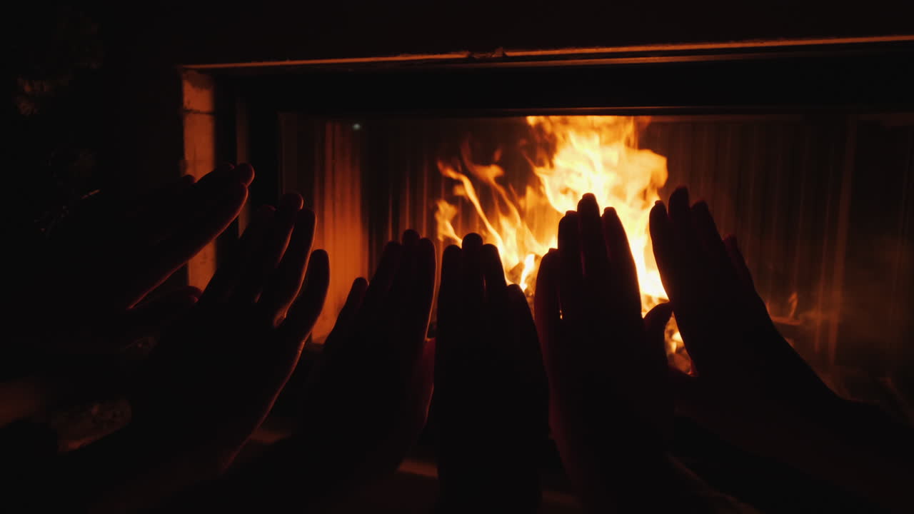 los padres con un niño se calientan las manos junto al fuego de una chimenea