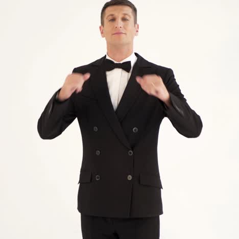 handsome man in a suit with bow-tie is posing in front of a mirror at the exit of the room. parody of the gentleman on the white background