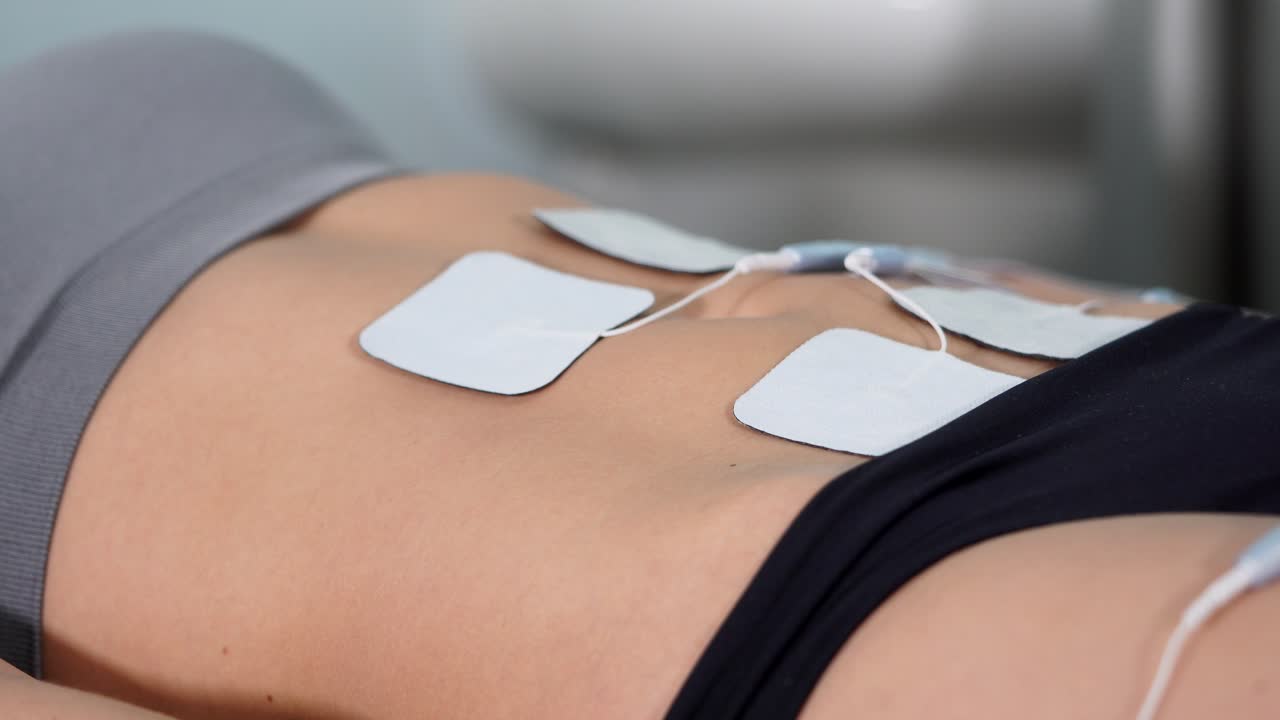 Woman receiving TENS unit treatment for abdominal pain