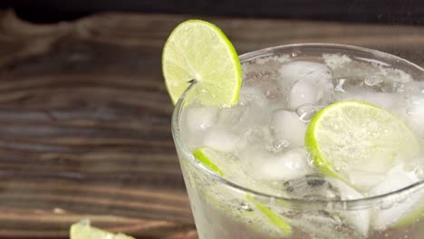 Soft-drinks-with-lemon-slice-and-ice-cubes,-pouring-full-glass---studio-shot