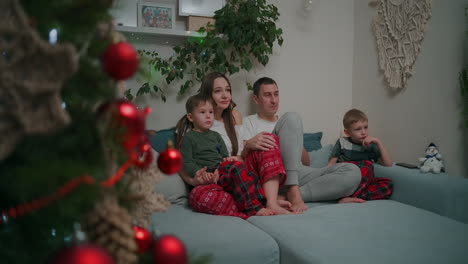 Family-of-three---father-mother-and-tow-son-watching-TV-in-the-evening.-Togetherness-quarantine-stay-home.-High-quality-4k-footage