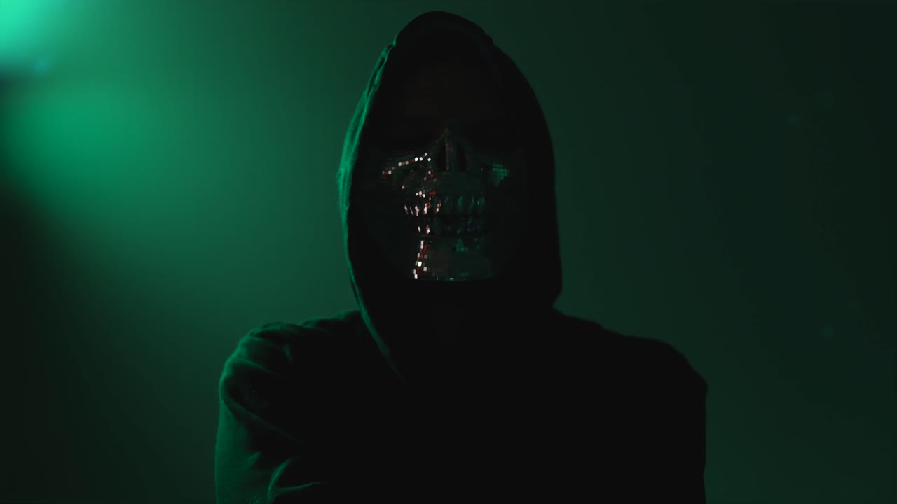 Anonymous Hacker in Hood and Mask with Crossed Arms Looking Directly at Camera – Represents Malware, Scam, Internet Crime and Cyberattack