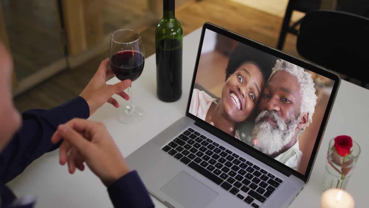 Mid section of african american woman drinking wine while having a video call on laptop at home