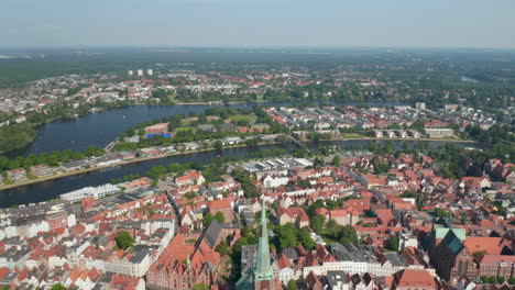 Aerial-panoramic-view-of-river-dividing-old-town-from-other-neighbourhoods.-City-surrounded-by-woods.-Luebeck,-Schleswig-Holstein,-Germany