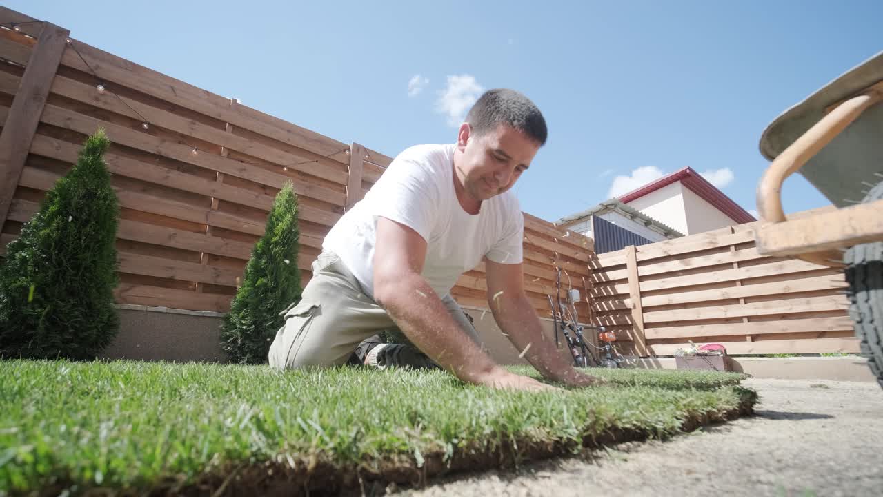 잔디 설치 및 조경 프로젝트를 위해 뒷마당 정원에 소드 풀을 는 사람, 주거 마당의 신선하고 푸른 잔디를 위해 집 개선 및 야외 유지에 초점을 맞추고 있습니다.