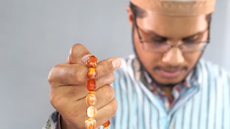 man praying with prayer beads