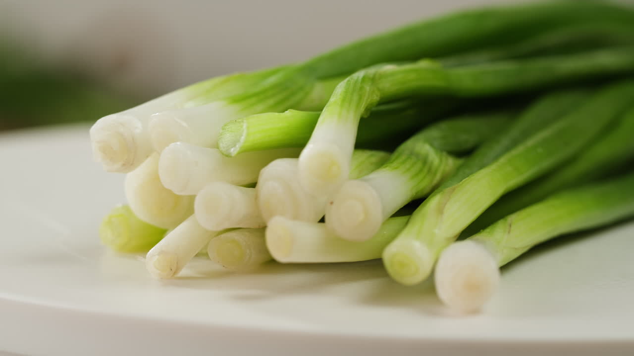 Cutting fresh green onions on a cutting board, close up chef cooking green vegan salad.