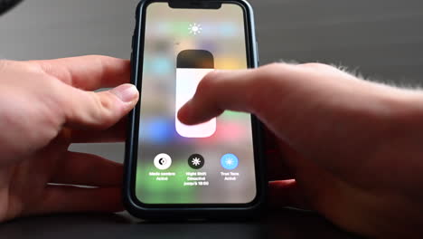 A phone user change the luminosity parameter in the settings, adjusting the brightness to his confort