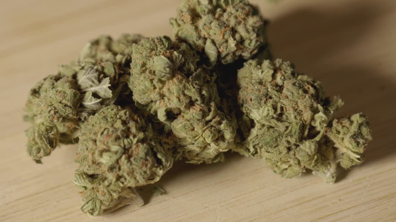 Medical Cannabis Or Marijuana Buds With Shadow On The Wooden Board. - close up shot