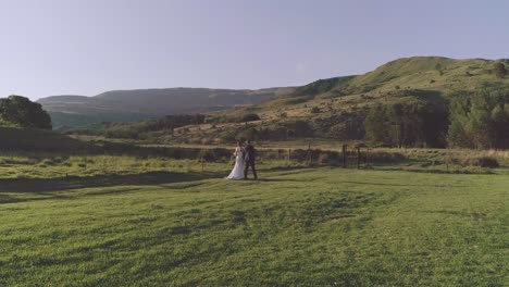 couple walking outside on green grass towards a mountain slow motion