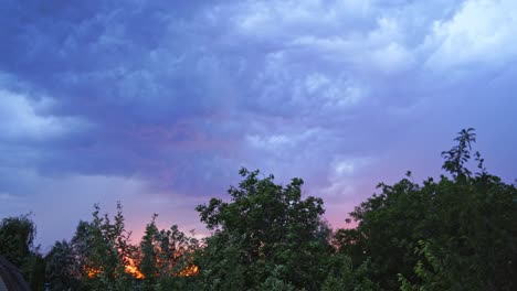 sparkles of lightning on the cloudy sky. strong wind moves the trees under the dark blue sky at sunset in summer. lightning before the rain outdoors.