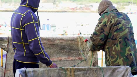 Dos-Hombres-Manejando-Una-Red-De-Pesca-En-Un-Día-Soleado