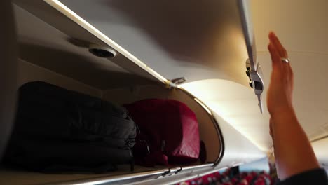 Closing-overhead-compartment-with-luggage-before-airplane-flight