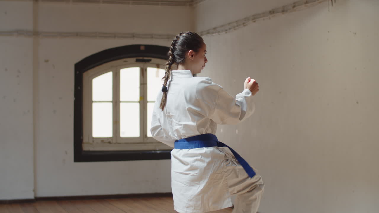 가라테 동작을 수행하는 집중된 소녀의 추적 샷