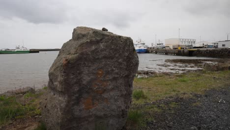 gran roca en primer plano con un barco al fondo ubicado en grindavik, islandia con un video de cardán caminando hacia adelante en cámara lenta