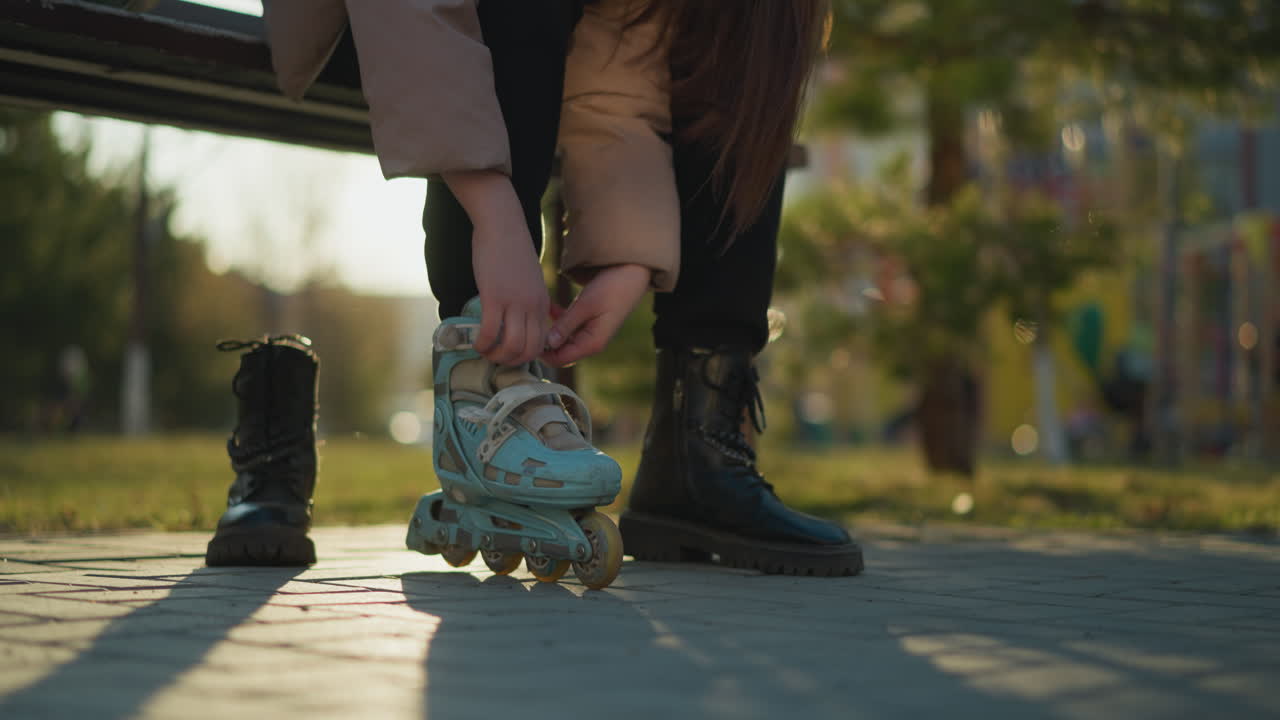 A close-up shot of a person removing their light blue rollerblades and putting on black boots in a park during a sunny day. transition between skating and walking, highlighting the focus on footwear