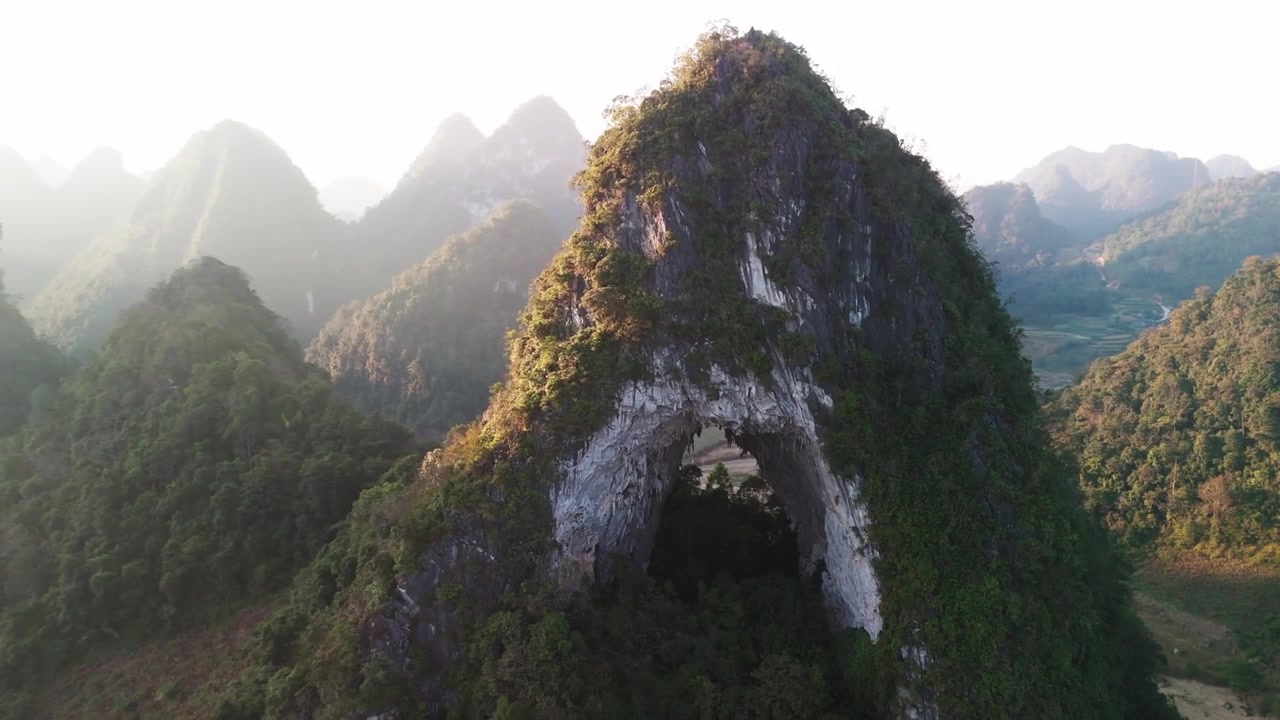 Cảnh quay drone điện ảnh bay ra xa khỏi lỗ tròn độc đáo trên Núi Mắt Thần (Mắt Thiên Thần). Tiết lộ phong cảnh núi đá vôi karst hùng vĩ và những thung lũng xanh tươi của Cao Bằng, miền Bắc Việt Nam
